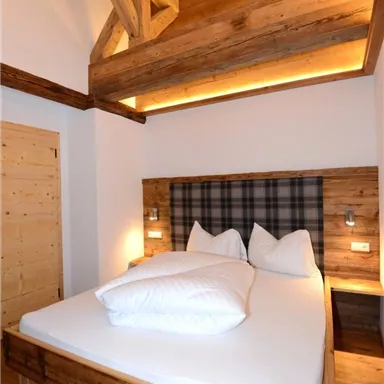 Ein modernes Schlafzimmer mit holzverkleideten Wänden und einer gemütlichen Bettgestaltung. Die Atmosphäre ist warm und einladend.