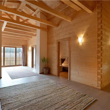 A bright room with a wooden ceiling and a large window. The floor is carpeted and there is a cozy atmosphere.