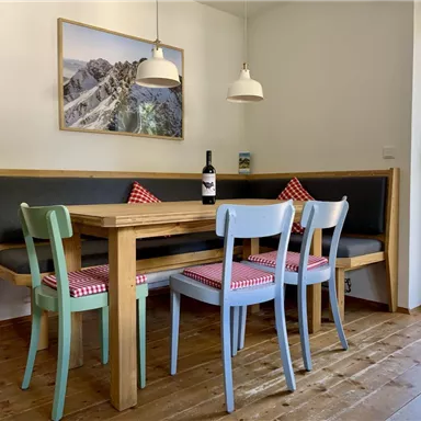 A cozy dining area with a wooden table and colorful chairs. The room has large windows and a touch of coziness for a friendly atmosphere.