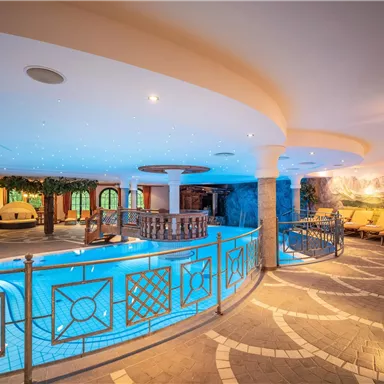 An elegant wellness area with a blue pool and comfortable loungers. The atmospheric lighting creates a relaxed atmosphere.