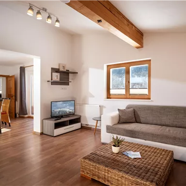 A modern living room with a cozy sofa and a coffee table. The large windows provide plenty of daylight and a bright atmosphere.