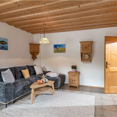 A cozy living room with a gray couch, a wooden table, and decorative pictures on the wall. The warm wood details create an inviting atmosphere.