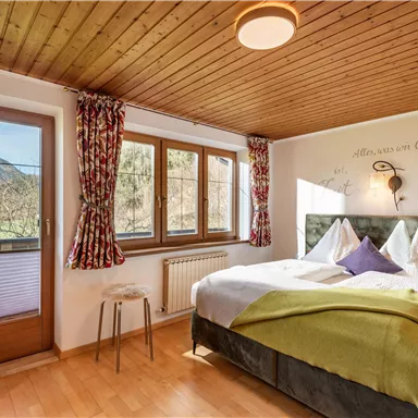 Ein gemütliches Schlafzimmer mit einem Doppelbett und bequemen Kissen. Große Fenster bieten einen schönen Ausblick auf die Natur.