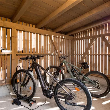 A bike parking area made of wood with two motorcycles. The space is brightly lit and has an airy atmosphere.