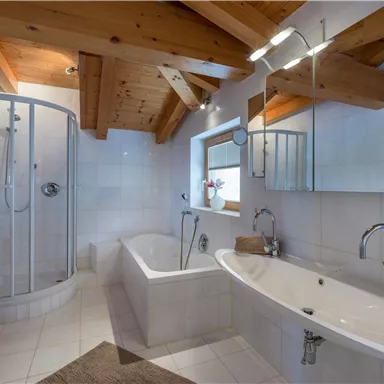 A modern bathroom with a shower and a bathtub. The wooden ceilings and mirrors create a stylish ambiance.