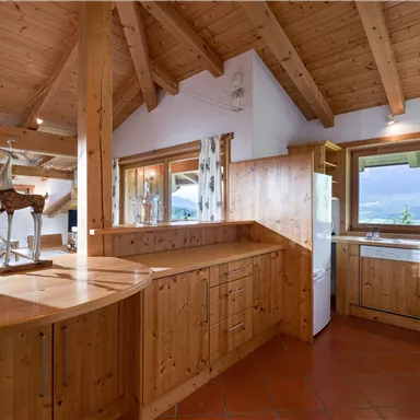A modern kitchen with wooden cladding and open shelves. Large windows provide plenty of light and a beautiful view.