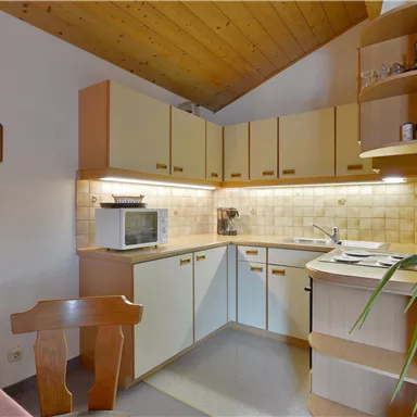 Eine helle Küche mit Holzdetails und modernen Geräten. Sie ist gut organisiert und bietet ausreichend Platz für die Zubereitung von Mahlzeiten.