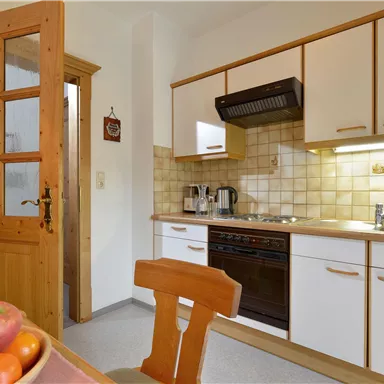 Eine moderne Küche mit Holzdetails und weißem Schrankdesign. Auf dem Tisch liegen frische Äpfel.