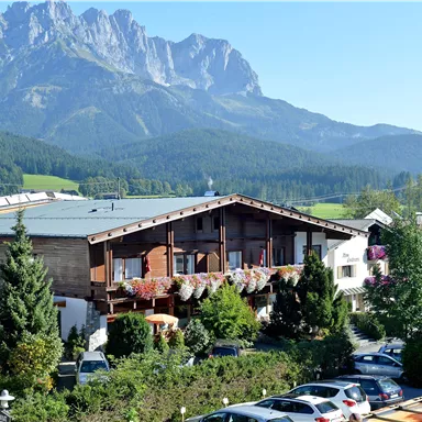 Ein malerisches Bergdorf mit traditioneller Architektur. Im Hintergrund erheben sich majestätische Berge unter einem klaren Himmel.