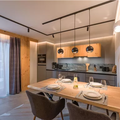 Eine moderne Küche mit einem Essbereich. Der Raum verfügt über Holzdetails und stilvolle Beleuchtung.