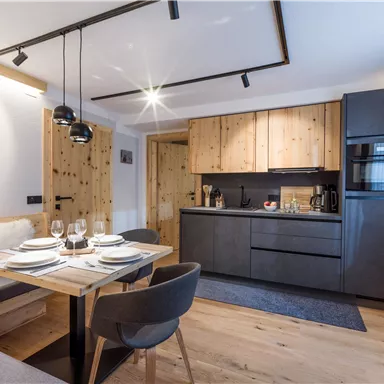 Eine moderne Küche mit Holzdetails und eleganten Möbeln. Der Essbereich ist geschmackvoll gedeckt und lädt zum Essen ein.