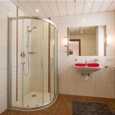 Ein modernes Badezimmer mit einer runden Duschkabine und hellen Fliesen. Der Raum ist gut beleuchtet und hat eine schlichte, elegante Ausstattung.