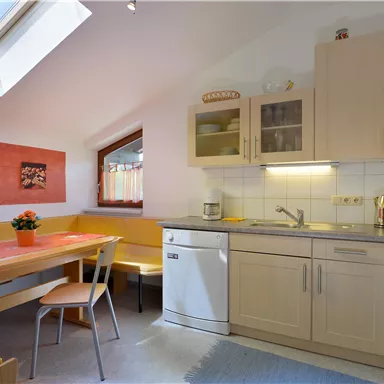 A bright kitchen with modern furniture and a cozy seating area. The room has a window with daylight and is designed in a friendly manner.