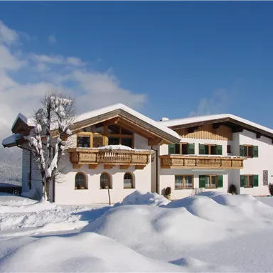 Ein modernes Haus im Schnee, umgeben von einer verschneiten Landschaft. Der klare blaue Himmel verleiht der Winteridylle einen schönen Kontrast.