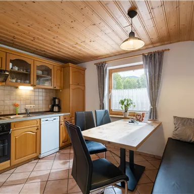 Eine gemütliche Küche mit Holzschränken und einem Esstisch. Der Raum ist hell und einladend, mit Platz für mehrere Personen.