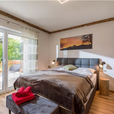 Ein gemütliches Schlafzimmer mit einem großen Bett und einem schönen Ausblick. Helle Farben und eine moderne Einrichtung schaffen eine einladende Atmosphäre.