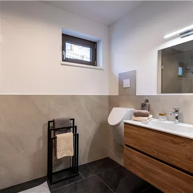 Ein modernes Badezimmer mit einer Glasdusche und einem Holzwaschbecken. Die Wände sind in neutralen Farbtönen gehalten, und es gibt einen großen Spiegel über dem Waschbecken.