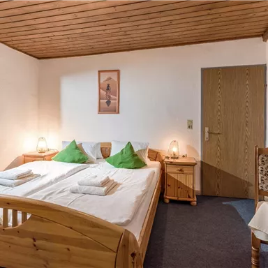 Ein gemütliches Schlafzimmer mit zwei Einzelbetten und Holzmöbeln. Der Raum ist freundlich und schlicht mit einem schönen Holzdecken.