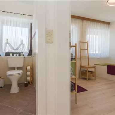 Ein modernes Badezimmer mit einer Toilette und hellen Farben. Der Bereich ist gut beleuchtet und hat eine freundliche Atmosphäre.