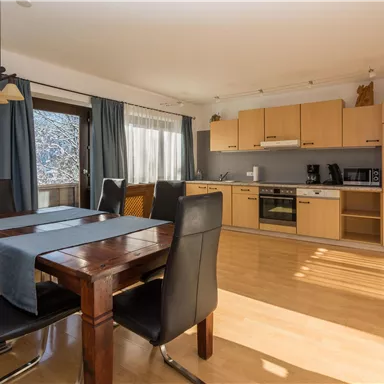 Eine moderne Küche mit einem Esstisch und Stühlen. Der Raum ist hell und freundlich eingerichtet.