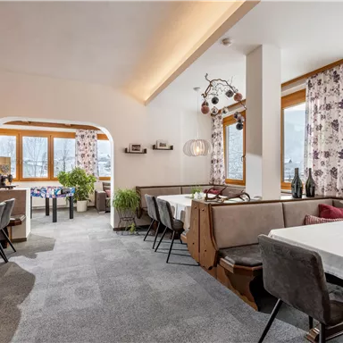 An inviting restaurant with bright windows and stylish furniture. The cozy atmosphere is enhanced by plants and modern lighting.