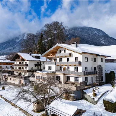 A beautiful hotel building in a snowy landscape. In the background are mountains and a clear sky.