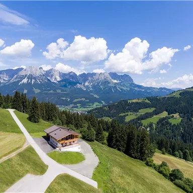 A beautiful mountain panorama with green meadows and a solitary chalet. The clouds in the sky give the scene a picturesque charm.