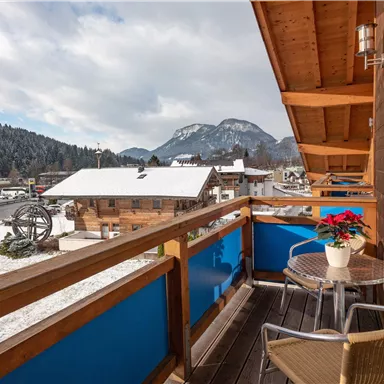 Ein schöner Balkon mit Blick auf ein verschneites Landschaft mit Bergen im Hintergrund. Die Atmosphäre ist gemütlich und einladend.