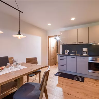 Eine moderne Küche mit einem Essbereich aus Holz. Die Räume sind hell und einladend gestaltet.