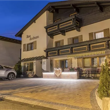 Ein charmantes Hotel mit traditioneller Architektur und einem einladenden Eingangsbereich. Der Außenbereich ist beleuchtet und schafft eine gemütliche Atmosphäre bei Nacht.