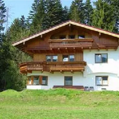 A beautiful, traditional chalet in the mountains. Surrounded by green meadows and tall trees.