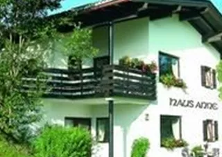 A modern house with a balcony and beautiful flowers. It is located in a green environment with trees and grass.