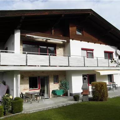 Ein hübsches Haus mit einem Balkon und einem Garten. Die Fassade kombiniert Holz und Putz und bietet viel Platz im Freien.