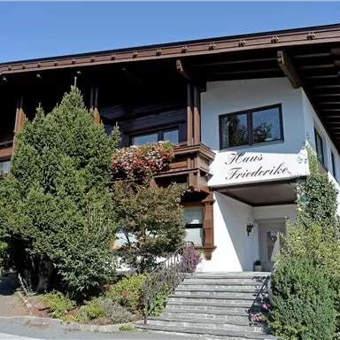 Ein charmantes Gebäude im traditionellen Stil mit einem gepflegten Garten. Der Name "Haus Friedrich" ist gut sichtbar über dem Eingang.