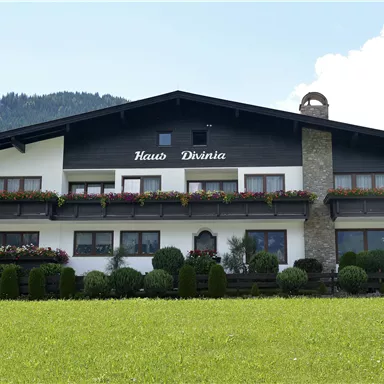 Ein gemütliches Haus mit Balkonen und Blumenfenstern. Die Wohnung hat einen sonnigen Standort mit einer schönen Berglandschaft im Hintergrund.