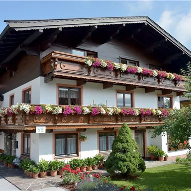 A beautiful building in traditional style with flowers on the balconies. Surrounded by well-kept gardens and a clear sky.