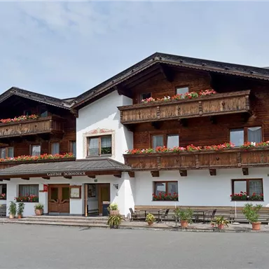 A charming wooden house with balconies and blooming flowers. It is located in a quiet setting with some trees and a clear view.