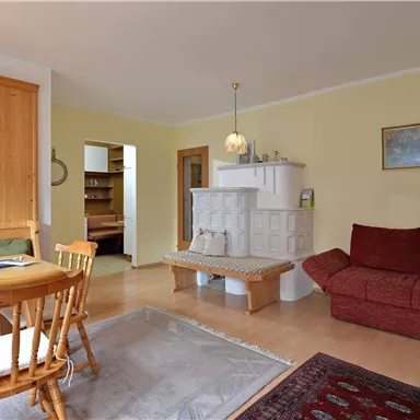 Eine helle und gemütliche Wohnung mit einem Essbereich und einer roten Couch. Die Wände sind in sanften Farben gestrichen und es gibt eine Holzverkleidung.