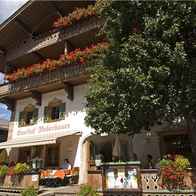 Ein charmantes Gasthaus mit blühenden Blumen auf dem Balkon. Die Fassade ist im traditionellen Stil gehalten und lädt zum Verweilen ein.