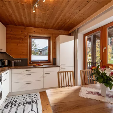 Eine moderne Küche mit Holzdecke und weißen Schränken.