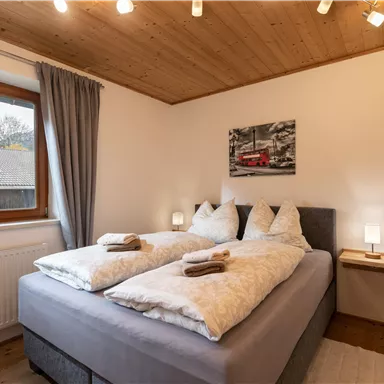 Ein gemütliches Schlafzimmer mit einem Boxspringbett (160 x 200) und einer Schlafcouch. Natürliches Licht fällt durch das Fenster und schafft eine einladende Atmosphäre.