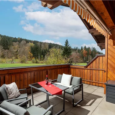 Ein gemütliche, grosse Terrasse mit modernen Möbeln und Blick auf eine grüne Landschaft.