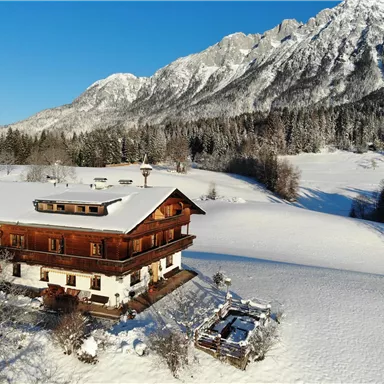 A charming wooden house in the snow with a view of majestic mountains. The surroundings are wintry and covered with white snow.