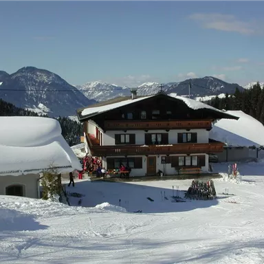 Ein gemütliches Chalet in einer verschneiten Berglandschaft. Die Umgebung ist mit frischem Schnee bedeckt und die Berge sind klar sichtbar.