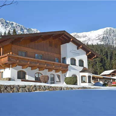 A cozy chalet in the snow with a picturesque mountain view. The surroundings are surrounded by forests and mountains.