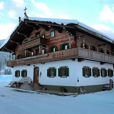 Ein traditionelles Holzhaus im Snow, umgeben von schneebedeckten Bäumen. Der Himmel ist blau und klar.