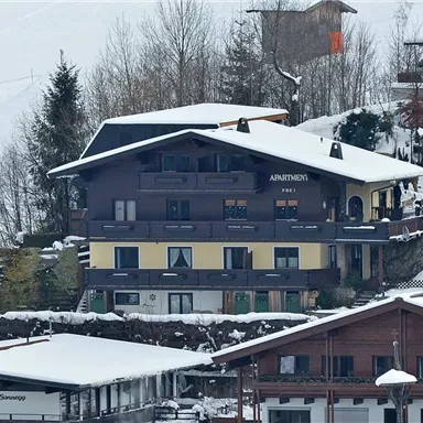 Ein malerisches Gebäude im Schnee mit einem traditionellen Alpenstil. Umgeben von Bäumen und einer ruhigen Winterlandschaft.