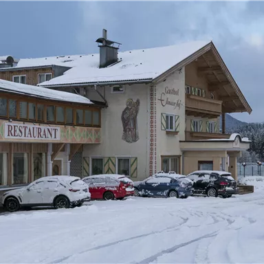 Ein Restaurantgebäude im Schnee mit mehreren Autos auf dem Parkplatz. Die Umgebung ist winterlich und der Himmel ist bewölkt.