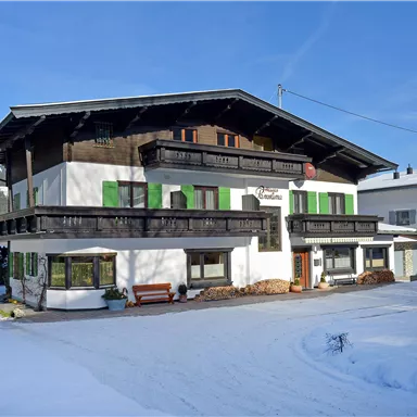 A charming building in Alpine style, surrounded by snow. The green shutters give the house a special accent.