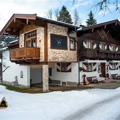 A beautiful chalet in winter, surrounded by snow. The architecture combines traditional and modern elements.